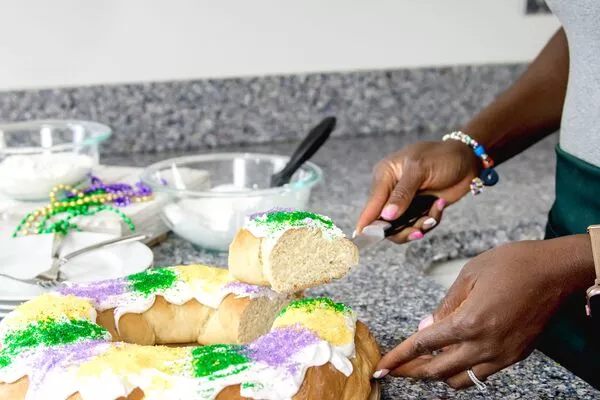 Zainab Storms cutting a slice of king cake with domino sugar