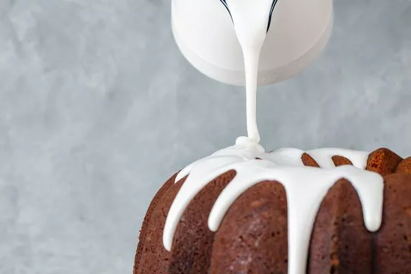 pouring domino powdered sugar glaze onto bundt cake