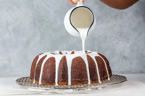 pouring domino powdered sugar glaze onto bundt cake