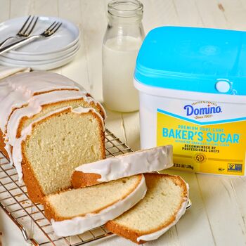 Sliced pound cake displayed on a kitchen counter next to a tub of Domino® baker's sugar
